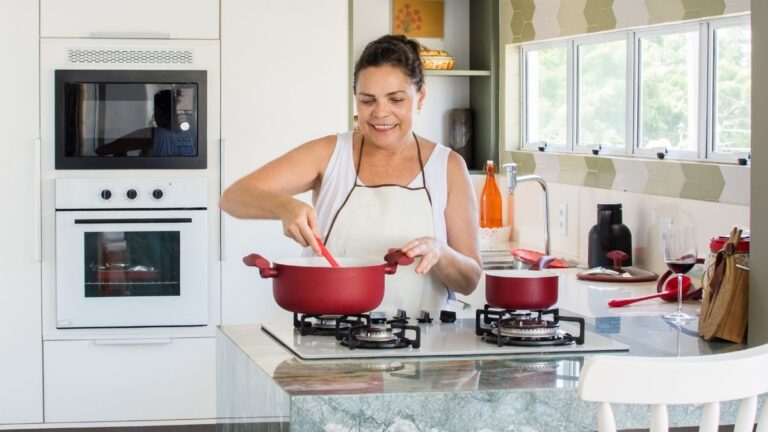 mulher preparando refeições na cozinha usando panelas antiaderente vermelhas