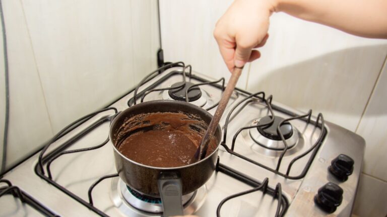 mão mexendo doce na panela que está em cima de um fogão